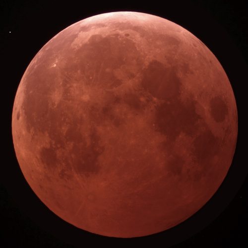The Moon during a total lunar eclipse, glowing a deep copper red